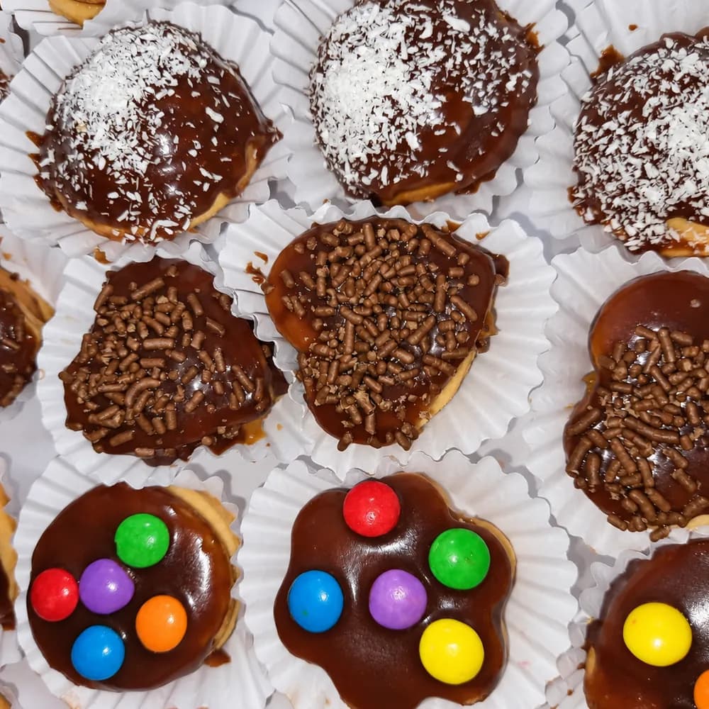 Bandeja de masitas dulces bañadas en chocolate, decoradas con granas de colores, coco rallado y confites, servidas en pirotines de papel